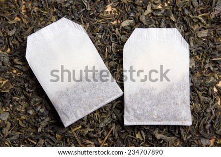 two tea bags over dried tea leaves background