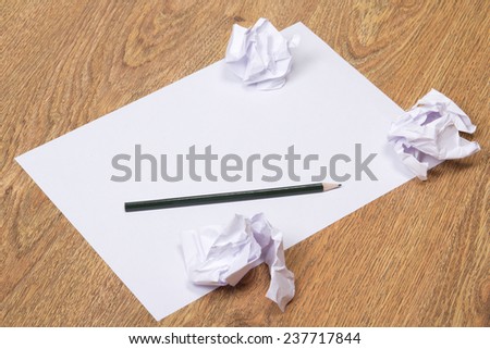 black pencil on clear white paper with crumble paper balls on wooden table background