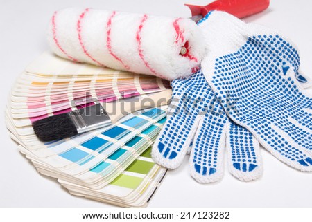 close up of painter\'s tools - brushes, work gloves and colorful palette over white background
