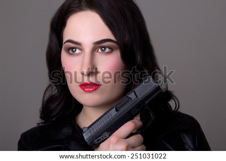 close up portrait of beautiful woman with gun over grey background