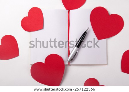 love letter concept - note book, pen and red paper hearts
