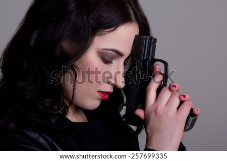 portrait of beautiful woman with gun over grey background
