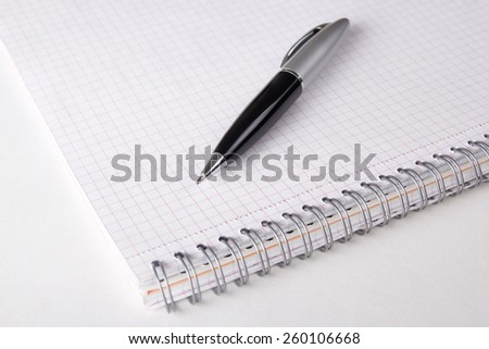 close up of note book with checked pages and pen on the table
