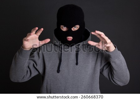 angry man criminal, robber or burglar in black mask over grey background