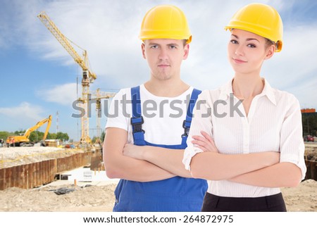 young man builder and business woman architect in helmet at construction site