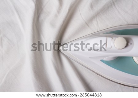 close up of iron ironing wrinkled white cotton linen