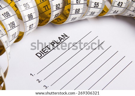 close up of paper with diet plan and yellow measure tape