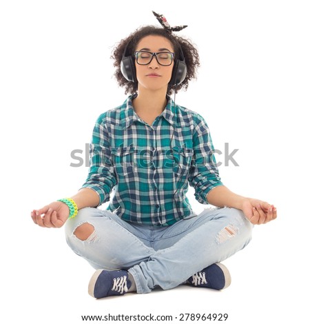 happy african american teenage girl sitting in yoga pose and listening music isolated on white background