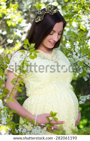 young beautiful pregnant woman with cherry tree flowers