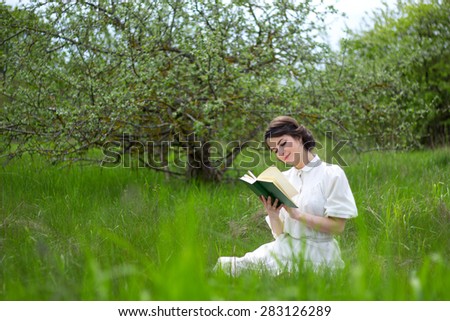 young beautiful woman reading book on summer meadow