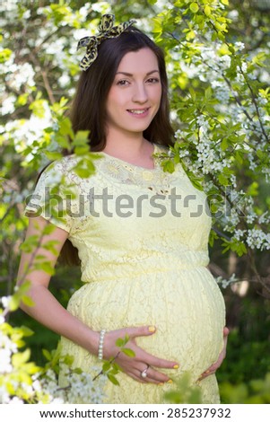 portrait of young beautiful pregnant woman with cherry tree flowers