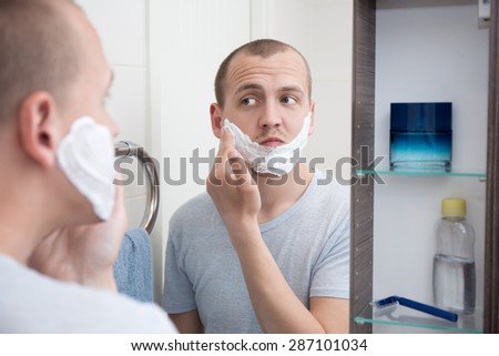 portrait of handsome young man applying shaving foam to his face