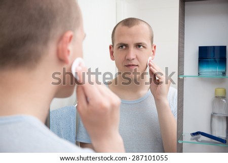 happy young man washing her face in bathroom