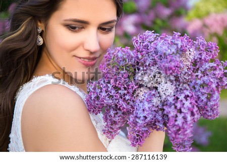 close up portrait of happy beautiful bride with big bouquet of lilac flowers