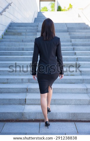 career concept - back view of young business woman on stairs