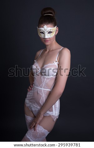 portrait of beautiful sexy woman in white lingerie and mask over grey background