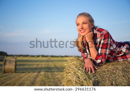 country concept - happy young beautiful romantic woman lying on haystack in field