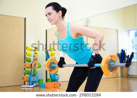 bodybuilding concept - sporty woman exercising with barbell in gym