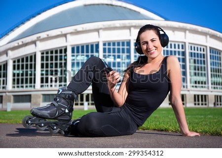 happy beautiful woman in roller skates sitting and listening music