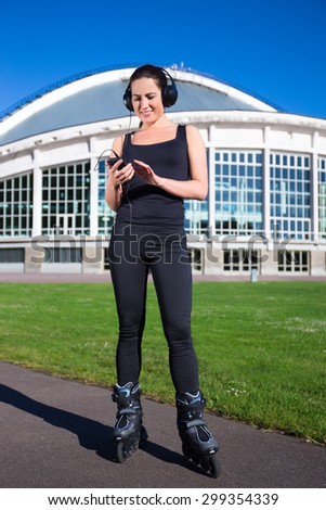 cheerful girl in roller skates listening music in summer park