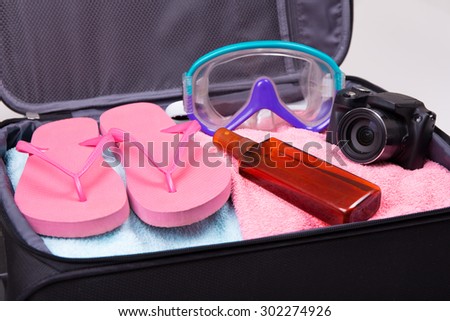 travel or vacation concept - packed suitcase full of vacation items