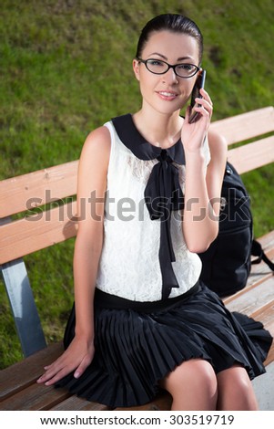 smiling student or school girl talking on mobile phone in park