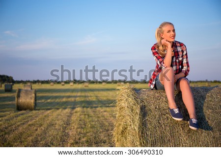 country concept - happy beautiful woman sitting on haystack in field