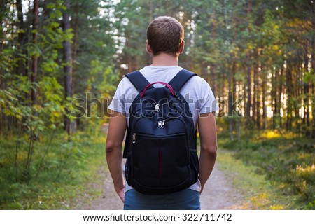 rear view of man with backpack hiking in forest