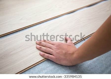 close up of male hands installing new laminated wooden floor