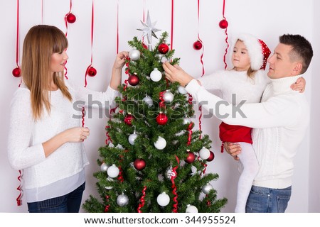 portrait of happy young family decorating Christmas tree