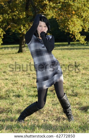 pretty girl in checkered dress posing in autumn park