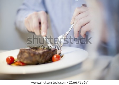 eating stake from plate with fork and knife man hands