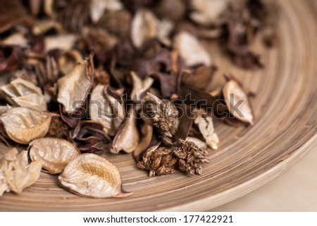 Fragrant blend of natural dried berries potpourri fruits in stylish round brown striped wooden plate on tawny brown homogeneous background