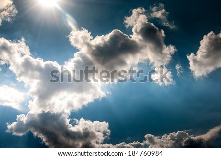 Dramatic hot summer sky with dark clouds with light flares