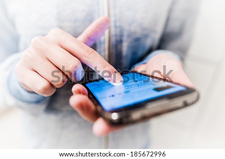 Young girl woman using modern communication holding touchscreen mobile phone on her hand doing sms chat write roll read close up image