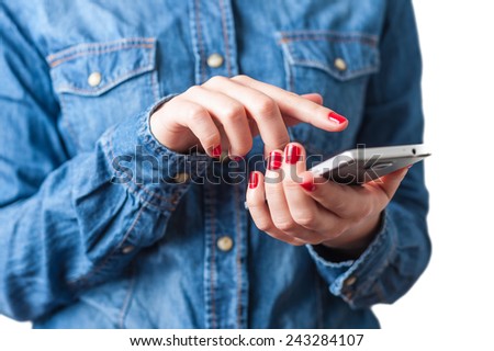 Young woman in blue denim shirt holding touch screen mobile phone in her red nail hands with small depth of field on isolated white background