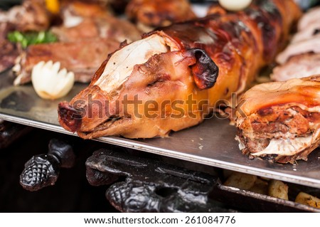 Roasted pig with garnish on hot metal platter