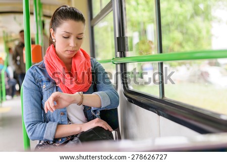 Young brown haired trendy woman looks at her watch while waiting to start the tram