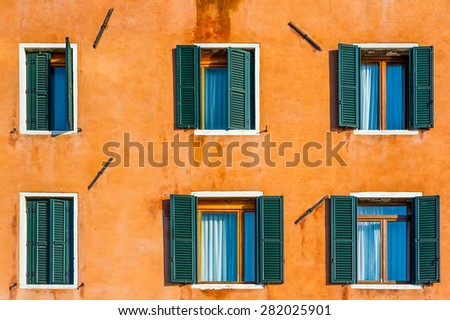 Old venetian building colorful orange painted facade with white framed facet windows