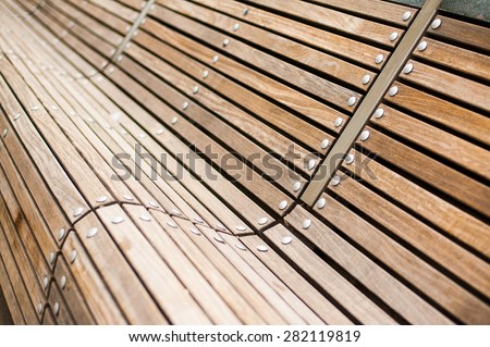 Modern curved s shaped brown wooden bench outdoor furniture detail as background image