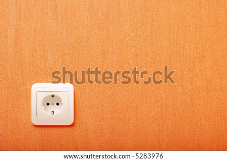 Electric wall plug at a orange wall