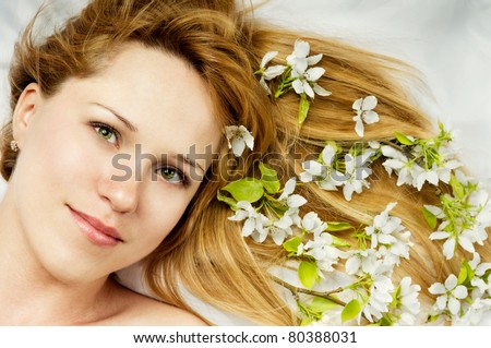 The beautiful girl with flowers lies on a silk pillow