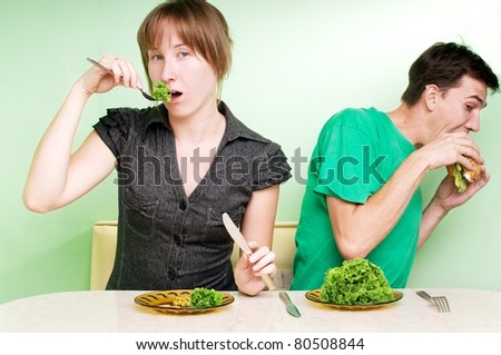 The women eats healthy food, and her husband secretly eats a hamburger.