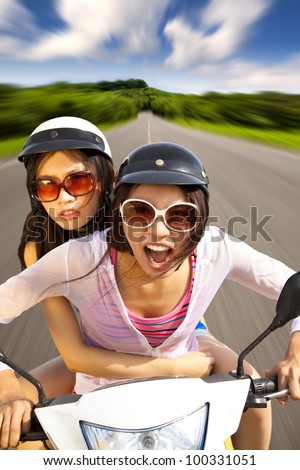 two girls riding scooter on the road