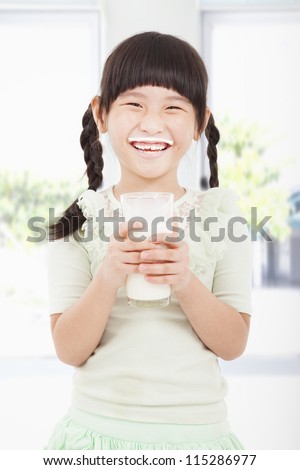 Happy  little girl holding a glass of fresh milk