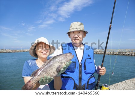 happy senior couple go fishing and showing big fish