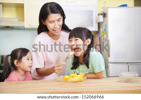 Mother and daughter eating fruits in the kitchen