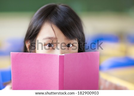 girl uses a book to cover her face