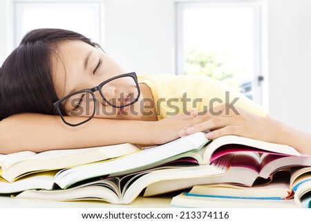 tired student girl with glasses sleeping on the books with room background