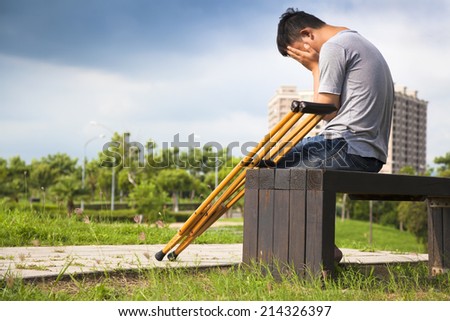 Injured Man with crutches sitting on a bench
